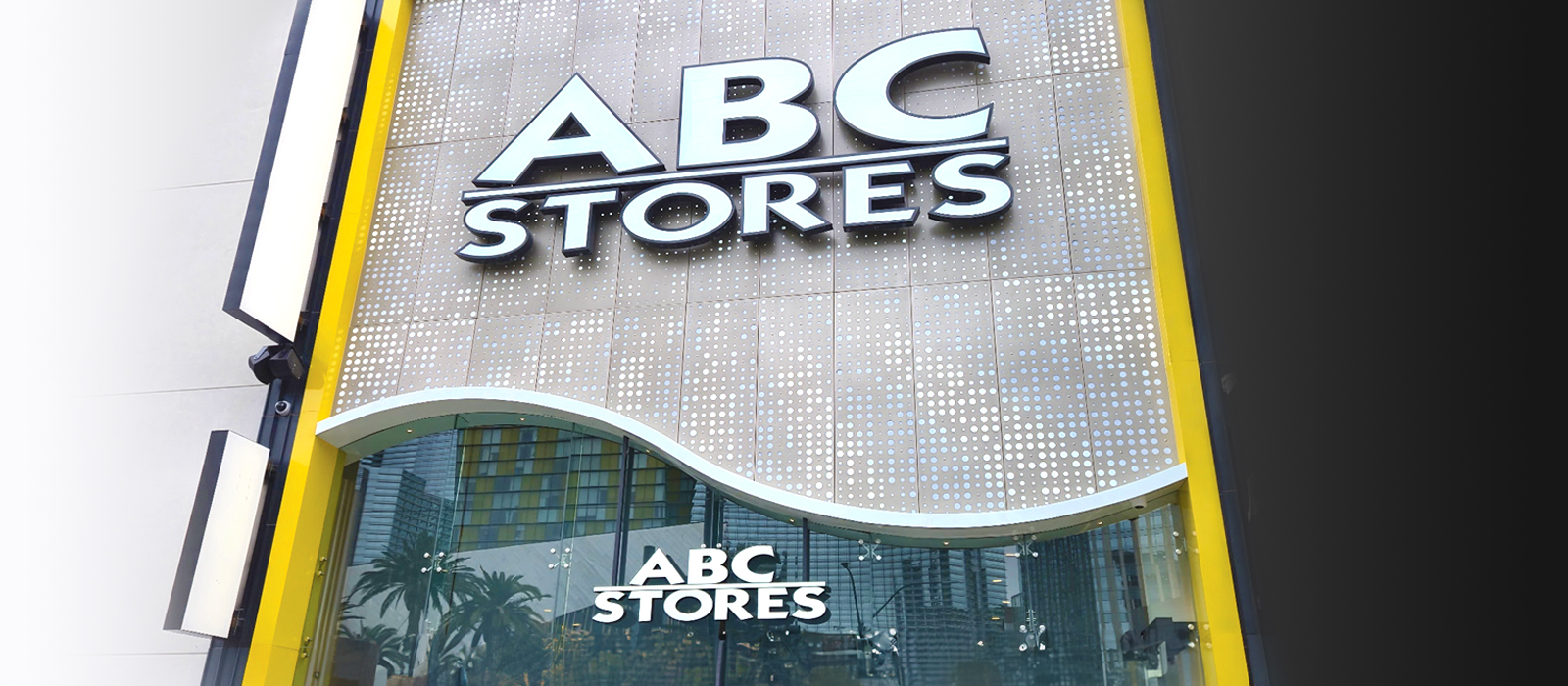 An image of the ABC Stores on the outside of the building, with panels as its background above a glass wall with a smaller ABC Stores logo.